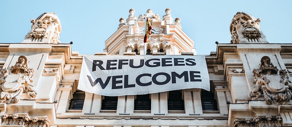 Refugees Welcome (qr) Transparent an der Fassade des Madrider Rathauses mit der Aufschrifft „Refugees Welcome“