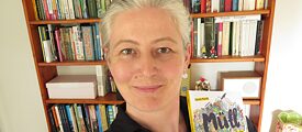 Frau mit Buch vor Bücherregal