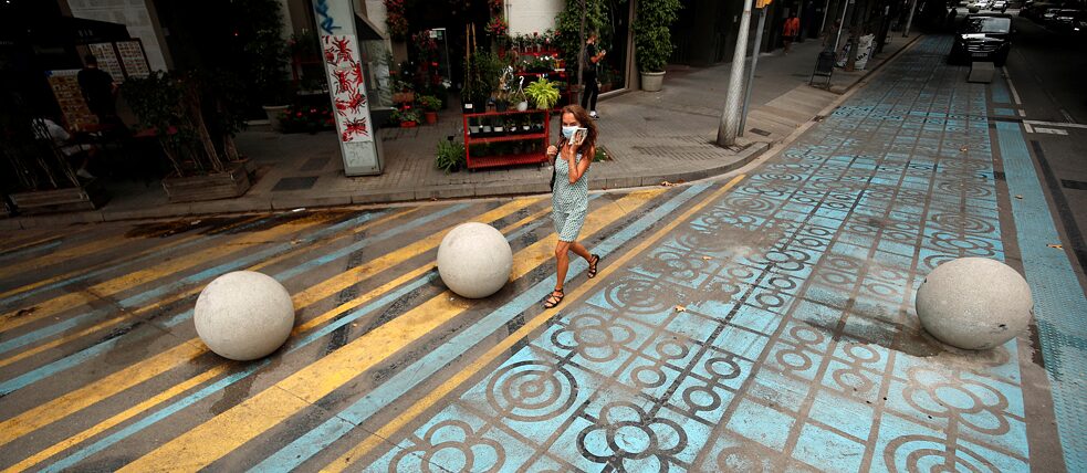 Eine Fußgängerin in Barcelona Blau- und gelb-bemalter Asphalt, auf dem eine Fußgängerin läuft