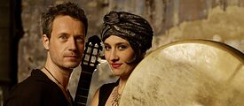 Musiker*innen mit Gitarre und Riesentamburin: Silvio Schneider und Karolina Trybała