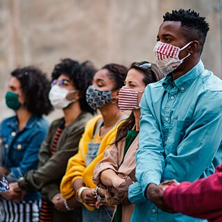 A group of women and a man holding hands in solidarity 