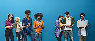 Junge Menschen unterschiedlicher Nationalität schauen in Tablets, Smartphones oder Laptops.	