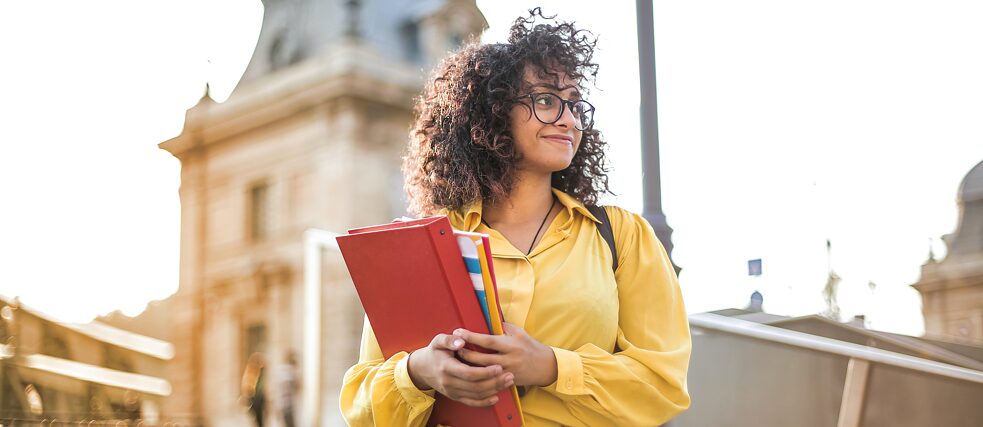 Eine junge Frau mit Büchern auf dem Arm