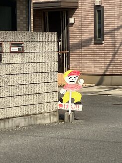 Cardboard sign on corner of house, it shows angry child