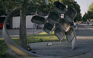 Památník pro oběti útoku v mnichovském nákupním centru Olympia v podobě ocelového kruhu s portréty a jmény devíti obětí objímá strom ginkgo biloba.