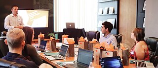 Menschen mit Laptops um einen Konferenz-Tisch. Ein Meeting.