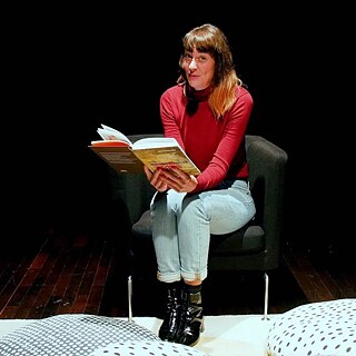 In der Kinderecke der Bibliothek hören Kinder einer Frau beim Geschichtenerzählen zu