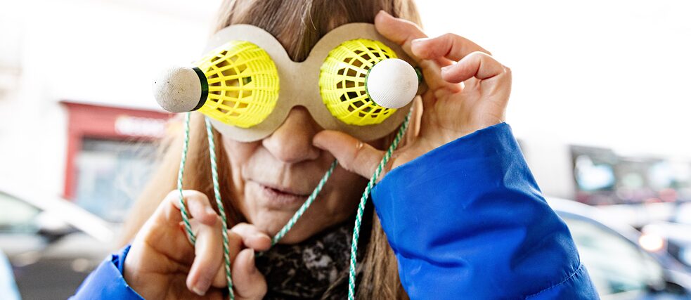 Eine Frau trägt eine Brille, auf der Federbälle angeklebt sind