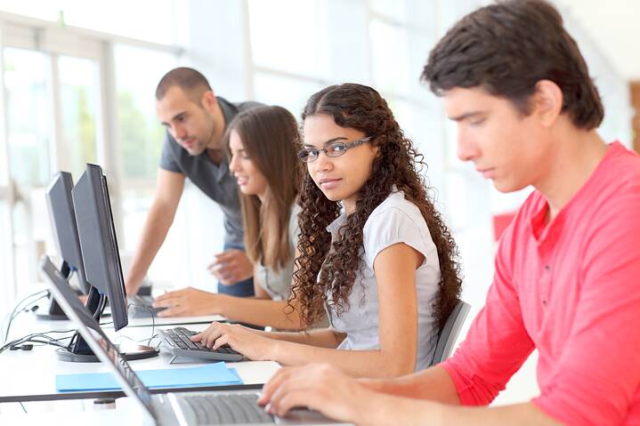 Schüler*innen am Computer Lehrperson betreut Schülerinnen und Schüler bei der Arbeit am Computer