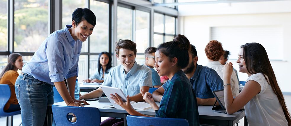 Lernszenarien zur Unterstützung einer zukunftsorientierten DaF-Didaktik Fünf Erwachsene um einen Tisch in einem großen, hellen Raum, Bücher auf dem Tisch, sie lernen