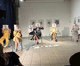 mehrere Menschen sitzen auf Stühlen und halten Fotos ihrer Gesichter vor ihre Gesichter