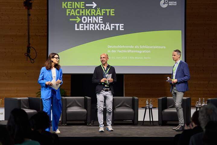 Keine Fachkräfte ohne Lehrkräfte: Personen auf der Bühne Amira El-Ahl (Moderatorin), Christoph Mohr (Bereichsleiter Vernetzungsprogramm) und Jan Sprenger (Bereichsleiter Fortbildungen) stehen auf der Bühne mit dem Titel der Veranstaltung.