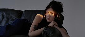 Juno liegt im Halbdunkel auf einem Sofa mit einem Lichtstrahl auf den Augen 
