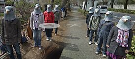 Eine Gruppe von Leuten mit Taubenmasken steht links und rechts  eines Wegs
