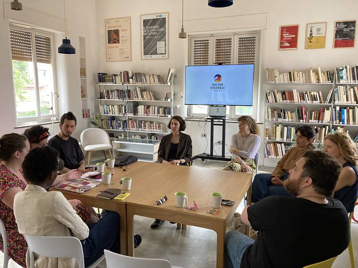 In der Bibliothek des Kultur Ensemble Palermo sitzen Teilnehmende um einen Tisch herum und diskutieren