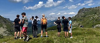 Jugendliche blicken auf die Berglandschaft.