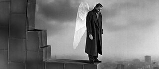 Ein Mann mit Engelsflügeln, der auf einem Hausdach steht.