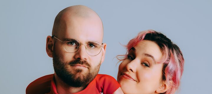 Das Duo vor einer weißen Wand.