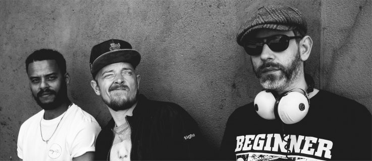 Beginner Die drei Musiker grinsend vor einer Wand