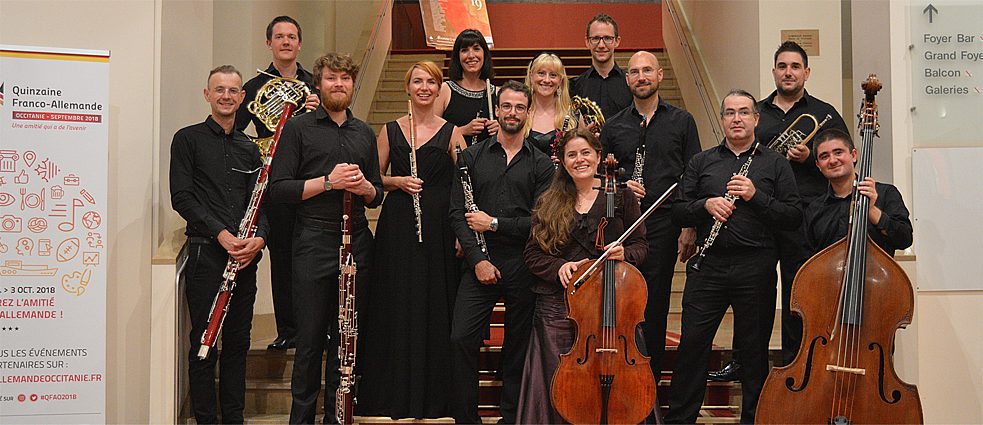 13 Musiker in schwarz mit ihren Instrumenten