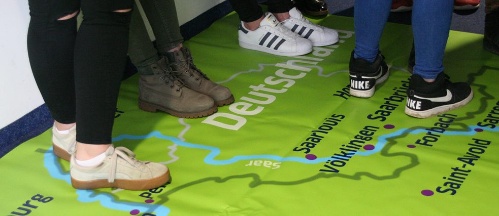 Deutschlandkarte am Boden, auf der Menschen stehen