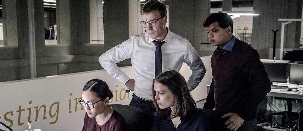 "Bad Banks - The Termination": Thao Hoang (Mai Duong Kieu) sits at a desk and looks at one of the many monitors that in front of her. Next to her is Jana Liekam (Paula Beer), behind her are the colleagues Adam Pohl (Albrecht Schuch) and Shanti Bhardevej (Utsav Agrawal). Everyone is watching what is happening on the screen in front of them.