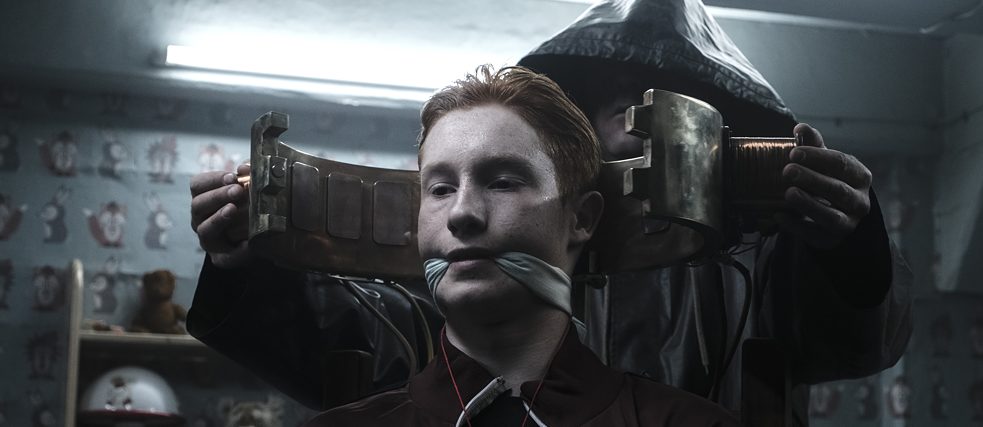 Dark - Eric Oberndorf bound and gagged sitting in a bunker, a dark figur behind him
