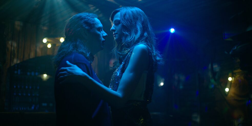 Still frame from the ZDF Series "Perfume" - "Perfume - Synthesis": Daniel "Toothless" Sluiter (Christian Friedel) and Elena Seliger (Natalia Belitski) dance together on a dark dance floor, they look each other in the eyes.