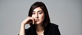 Junge Frau mit schwarzem Haar und schwarzem Anzug