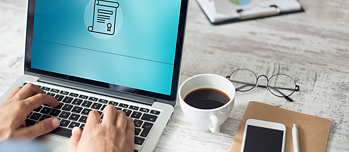 Hände die auf einem Laptop tippen, Kaffeetasse und Smartphone