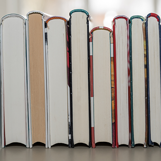 Trois piles de livres. Sur la première est posé un livre ouvert.