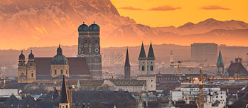 View of Munich and the Frauenkirche at sunset. The Alps can be seen in the background.