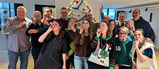 Kollegen und Kolleginnen stehen zusammen in einem weihnachtlich geschmückten Institutsraum