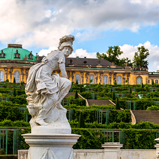 Ön planda bir heykel ile Sanssouci Sarayı'nın dış görünümü.