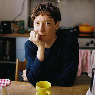 Bild von der Künstlerin Christine Gensheimer wie sie in der Küche sitzt