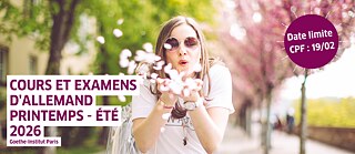 Person pustet lächelnd weiße Blüten in die Luft vor hellem Hintergrund.