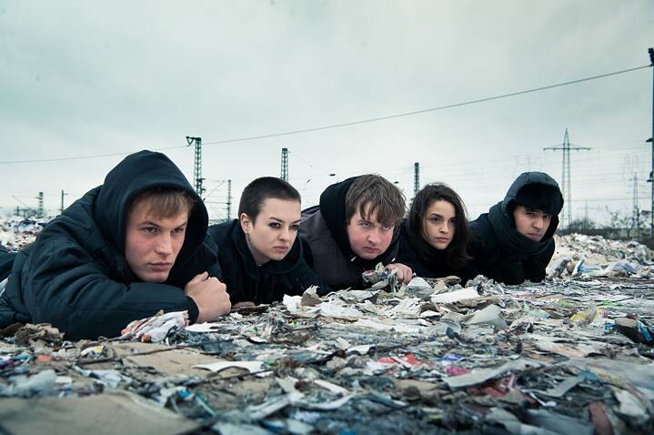 Still frame from the Netflix Germany original series "We are the wave":  The group of five teenagers lying in wait on top of large waste paper bails.