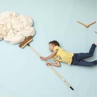 Fotoinstallation eines Jungen der mit Vögeln in der Luft schwebt und eine Wolke mit einem Besen wegschiebt.